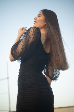 Beautiful and sensual young woman in a dress on a building rooftop in the golden hour