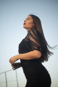 Beautiful and sensual young woman in a dress on a building rooftop in the golden hour