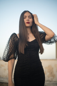 Beautiful and sensual young woman in a dress on a building rooftop in the golden hour