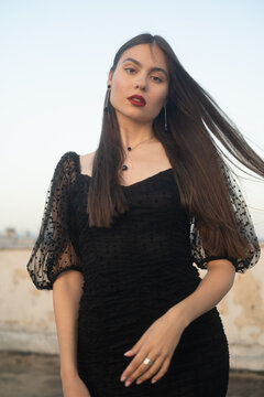 Beautiful and sensual young woman in a dress on a building rooftop in the golden hour