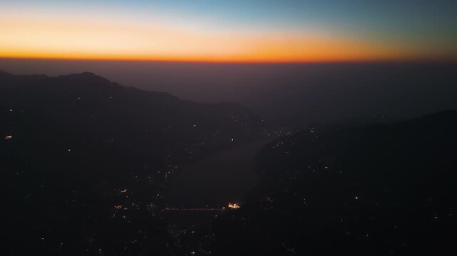 4K aerial drone shot of Nainital city during sunrise with glowing skyline and Himalayan mountains in the background, Uttarakhand, India.