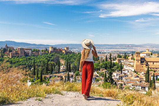 Woman tourist visiting Granada in Spain contemplating view of Alhambra and city landscape