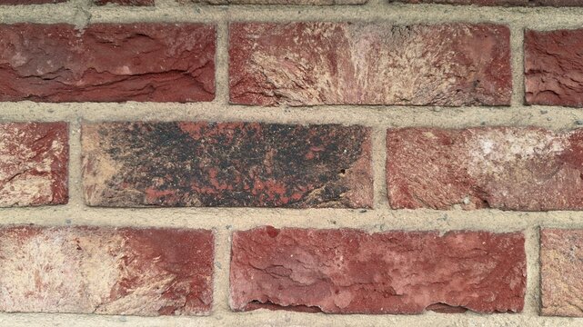 Red clinker brick wall background with dark burnt accent brick, rustic brickwork texture close up