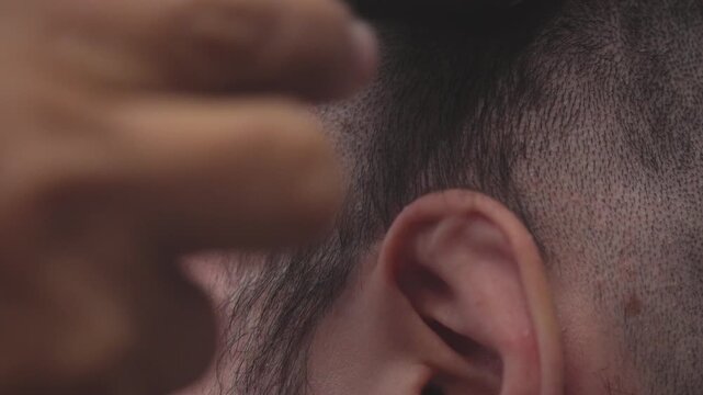 Extreme close-up of a hairdresser using an electric clipper to shave a man's head, creating a clean fade and stylish haircut in a salon
