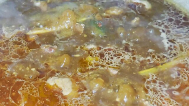 Boiling beef in wok during traditional Indonesian rendang cooking process, authentic Padang cuisine preparation