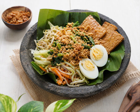 Traditional Indonesian Urap Vegetable Salad with Egg and Tempe on White Table