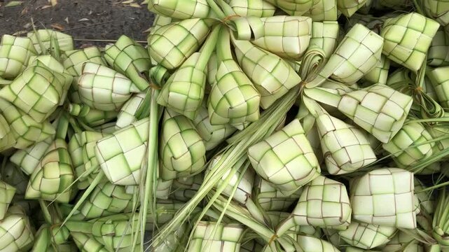 A large pile of freshly made ketupat, a traditional rice cake wrapped in woven palm leaves, ready for consumption.