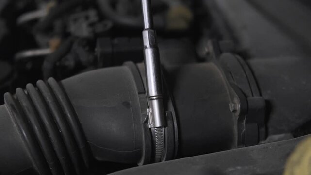 Close Up of Mechanic Hand Using a Socket Wrench Tool to Unscrew and Disassemble a Car Engine Part Under the Hood