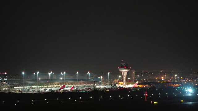 Commercial aircraft climbing after takeoff over illuminated Madrid Barajas terminal T4 at night