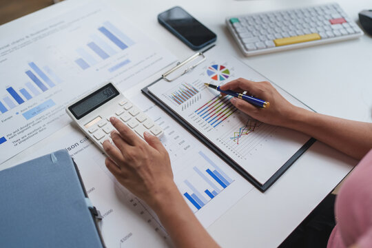 Person analyzing financial data using calculator and charts