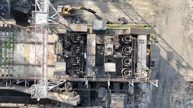 Industrial site with heavy machinery and equipment in operation, showcasing the gradual removal of debris and scrap metal from a large manufacturing facility