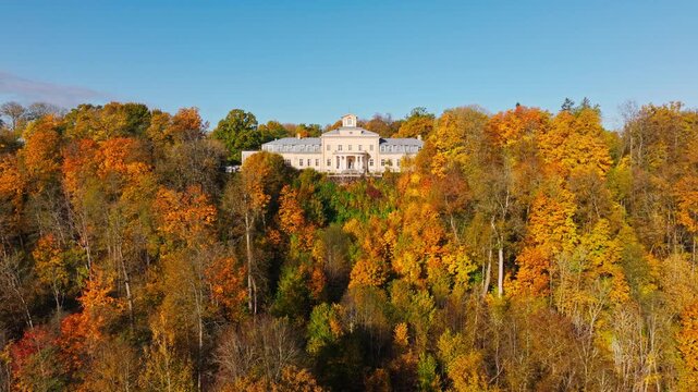 Bright morning sky illuminates Krimulda estate above colorful autumn landscape