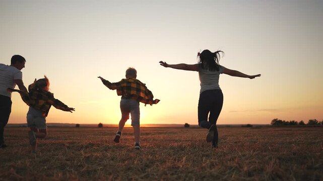 Family running in a field at sunset. Family, silhouette, running, park running together, sunset. Family lifestyle running together at sunset.