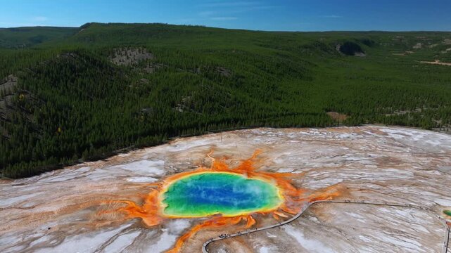 Grand Prismatic Springs lookout Mid Geyser Basin boardwalk Wyoming Yellowstone National Park aerial drone nature landscape view sunny morning blue sky colorful hot springs pools backwards motion
