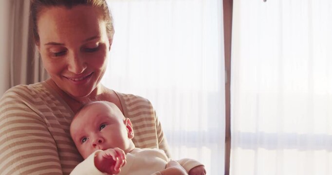 Happy adult mother is kissing newborn baby while holding him on her hands. Happiness of a loving mother's kiss.  Mother kissing baby's face. Mum loves and  cares of her infant baby.