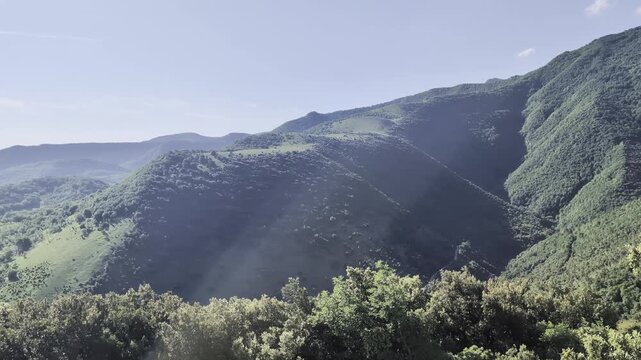 Clip video di colline verdi ricoperte di vegetazione, illuminate dal sole sotto cielo limpido. Atmosfera naturale, ampia e rilassante