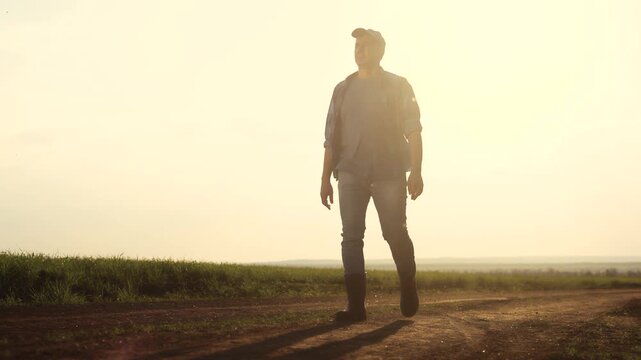 Man walking down dirt road. Silhouette of farmer walking in a field. Farmer working on lifestyle a field in evening. A individual strolling along a unpaved path.