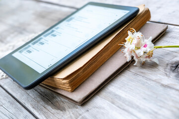ebook reader on stack old paper books on wooden table, electronic book, digital reading device and...
