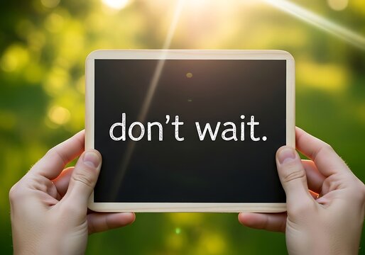 Hands holding a small chalkboard with the text dont wait written on it