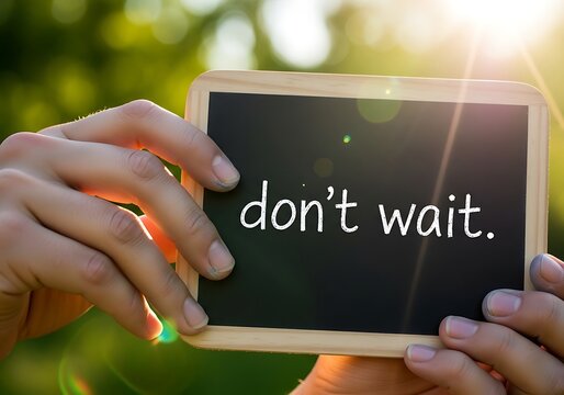 Hands holding a small chalkboard with the text dont wait written on it