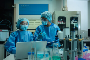 Medical or research scientist or doctor using looking at a test tube of clear solution in a lab or...