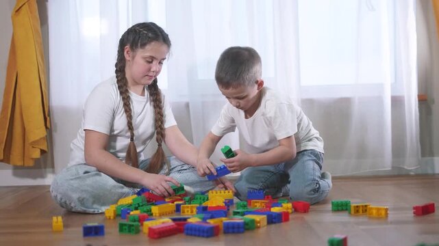 Two children playing with blocks. A group of children are assembling a construction. A group of lifestyle kids play with toys. Two kids stacking blocks.
