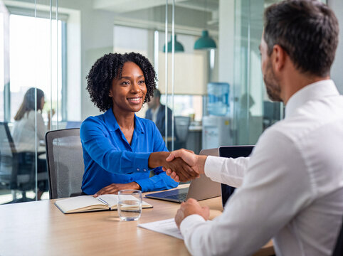 Smiling African American businesswoman shaking hands with a male colleague.