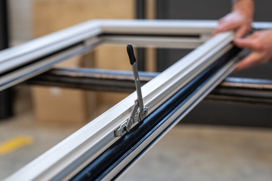 D&eacute;tail d&rsquo;un syst&egrave;me d&rsquo;ouverture int&eacute;gr&eacute; sur un ch&acirc;ssis aluminium en cours d&rsquo;assemblage dans un atelier de menuiserie sp&eacute;cialis&eacute;e.