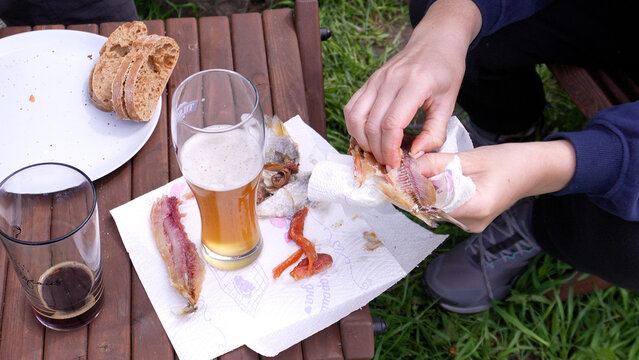 Beer and fish. A woman cleans a delicious fatty fish while relaxing outdoors.