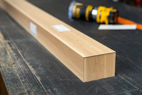 Pi&egrave;ce de bois rectangulaire avec finition soign&eacute;e pos&eacute;e sur un &eacute;tabli d&rsquo;atelier avec outils de menuiserie en arri&egrave;re-plan.