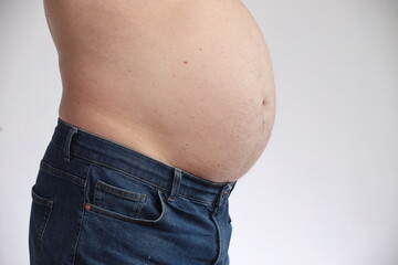 Naklejka premium Overweight man with belly in blue jeans. Concept of obesity, unhealthy lifestyle, excess weight and diet problems. Isolated on white background.