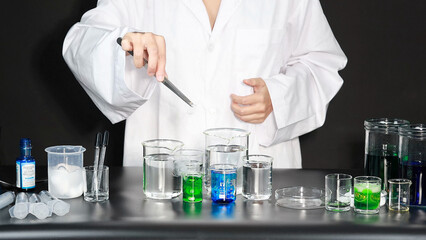 Fototapeta premium Scientist in White Lab Coat Using Tweezers to Conduct Chemistry Experiment