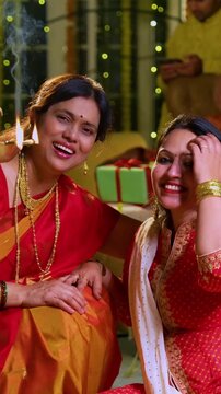 Lighting traditional samai with diya, Indian young girl in ethnic wear and senior mother joyfully celebrating Hindu festival Diwali in evening at home with festive decor and glowing diya illumination