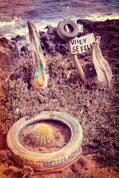 Tenerife, Canary Islands, Spain: old tyres and a wooden board with the spanish motto Vive y se feliz (Live and be happy) with view of Atlantic Ocean in the fishermen village of Puertito de Guimar