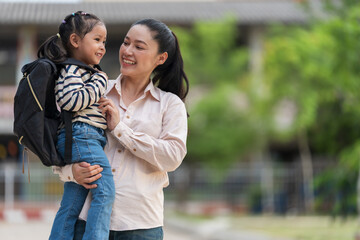 happy mother holding little daughter with a backpack, smilling and talking together on her first day of school © geargodz