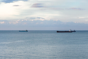 Fototapeta premium Tranquil sea horizon beneath pastel evening sky with distant boats and peaceful minimalist atmosphere