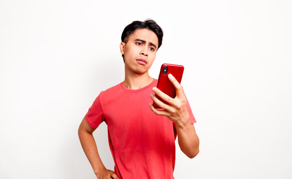 Confused young asian man looking at smartphone with doubtful face for technical problem and bad news concept