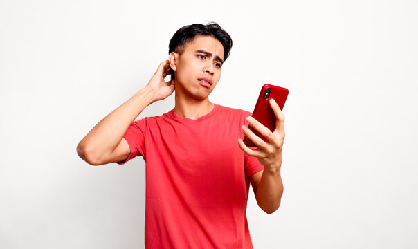 Confused young asian man scratching head while looking at smartphone for technical problem and complicated mobile app concept