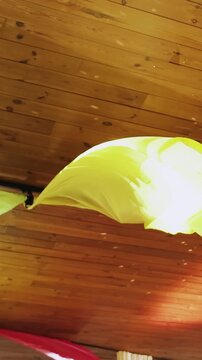 Vertical video. Yellow fabric decoration with light reflections inside a wedding venue hall. Event room interior setup with textile curtains under a wooden ceiling background.