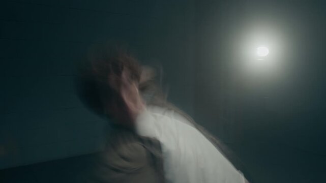 Medium shot of experimental dance performance of male dancer captured with chaotic motion blur and dynamic body trails in dark industrial studio, copy space