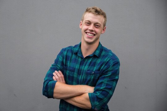 The Smiling Man in Plaid Shirt Standing Confidently Against Grey Wall