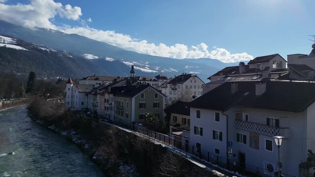 Ascending Drone Flight from Alpine Stream Revealing Townscape in South Tyrol, Italy