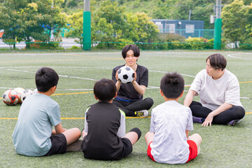 サッカーテクニックを説明する男性コーチと少年たち © Zoey106