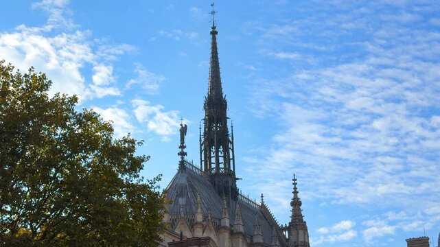 Gothic spire of the Sainte-Chapelle against a backdrop of autumn leaves and blue sky in Paris France