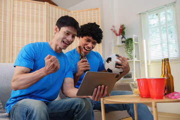 Fototapeta premium Excited Asian men watching soccer game on tablet at home