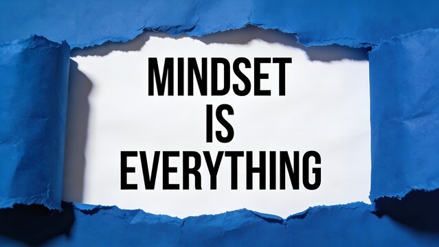 Bold black text stating mindset is everything revealed through a torn blue paper hole showing white background in a professional studio photography lighting setup style