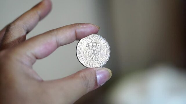 Close-up shot of a person holding an old 1945 Dutch East Indies 2&frac12; Cent coin with a blurred background.