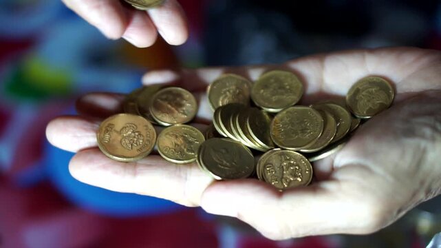 Hands counting vintage 500 rupiah coins as a symbol of transactions and old currency collection.
