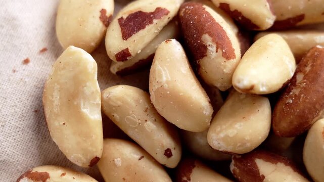 Peeled Brazil nuts scattered on natural beige textile surface. Healthy snack ingredient. Vegan nutrition products. Rotation