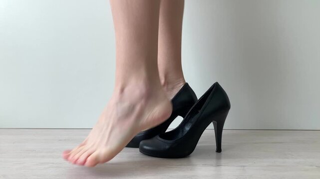 Woman takes off her black shoes. Relief and rest for tired feet, a feeling of release from the discomfort and tension caused by prolonged wearing of uncomfortable shoes. Taking care of own comfort